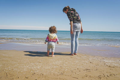 Rear view of woman standing at beach