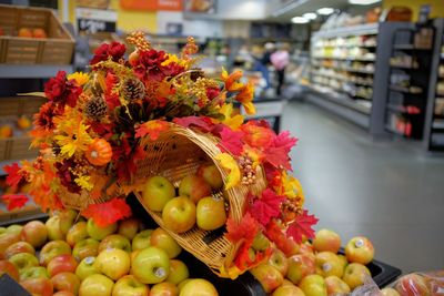 Close-up of apples with maple leaves in supermarket during autumn