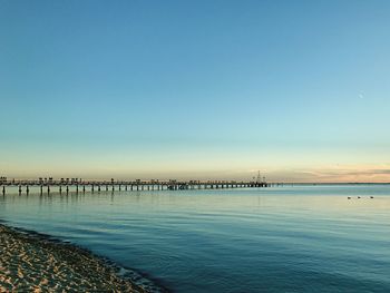 Pier over sea against clear blue sky