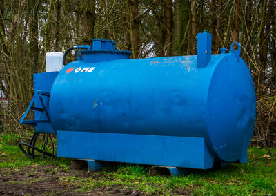 Blue container on field against trees in forest