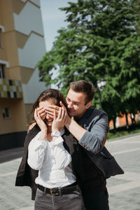 Man closing woman eyes from behind outdoors