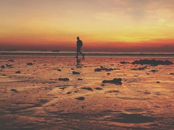 Silhouette person standing on beach against sky during sunset