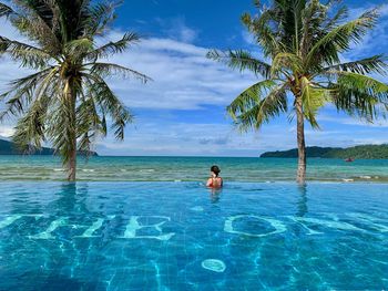 Woman in infinity pool against sky