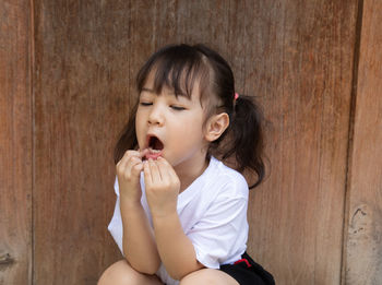 Cute girl with mouth open sitting against wall