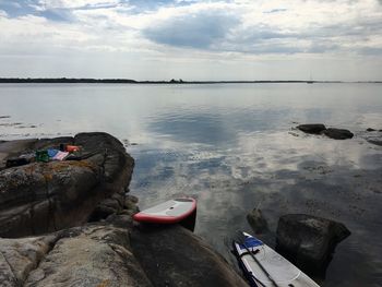 People sitting on rock by sea against sky