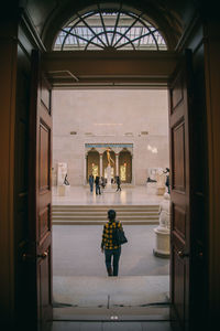 Rear view of woman walking in corridor of building