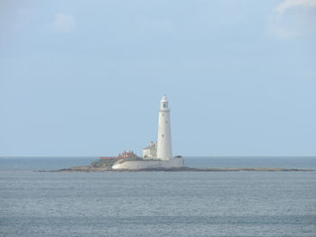 Lighthouse by sea against sky