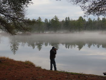 Man standing at lake with camera