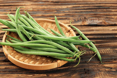 French green bean or buncis on bamboo plate, preparation cooking vegetarian food. on wooden table