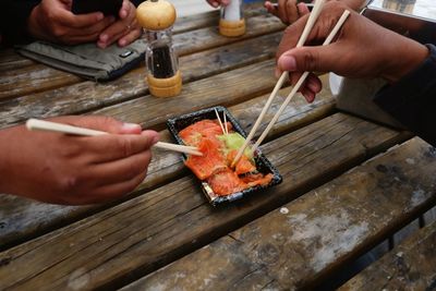 Close up of people eating sushi using chopstick