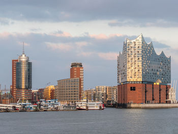 Sea by modern buildings against sky in city