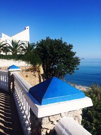 Swimming pool by sea against clear blue sky