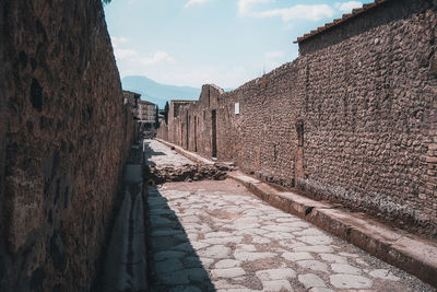 Footpath amidst buildings against sky