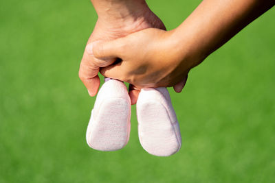 Cropped image of pregnant couple holding baby booties and hands