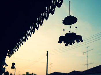 Low angle view of silhouette lanterns hanging against sky at sunset