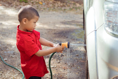 Side view of boy washing car