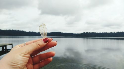 Close-up of hand holding ice cream against lake