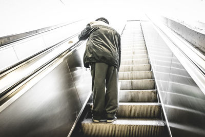 Low angle view of man walking on escalator