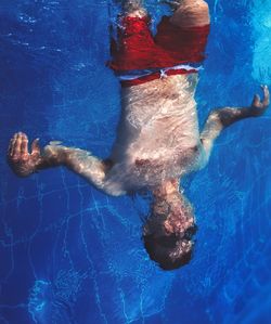 Reflection of man swimming in pool