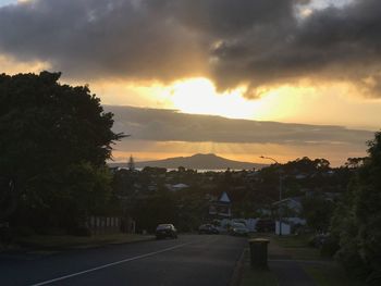 Cars on road against dramatic sky during sunset