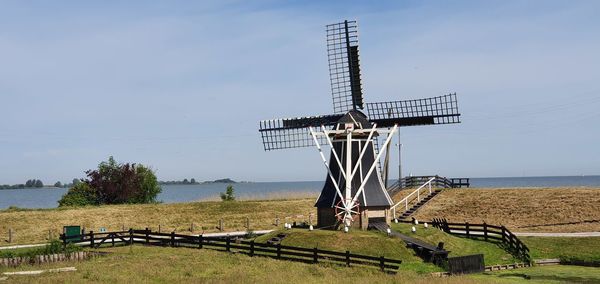 Traditional windmill on field against sky