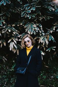 Portrait of young woman standing against plants