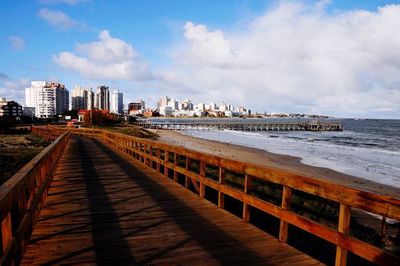 Pier on sea against cloudy sky