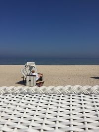 Lifeguard hut on beach against clear blue sky