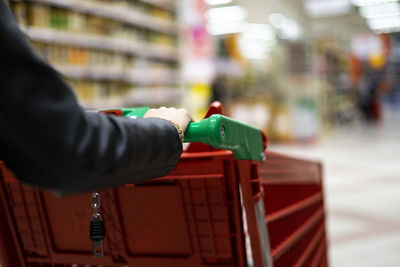 Woman carrying a red shopping cart in the supermarket.