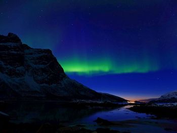 Low angle view of aurora borealis over river at night