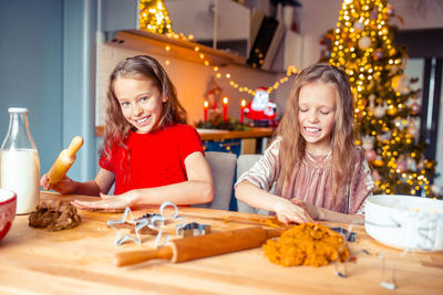 Portrait of smiling girl with sister making christmas cookies at home