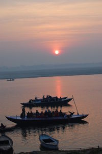 Silhouette boat in sea against sky during sunset