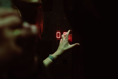 Cropped hand of woman pressing push button in elevator
