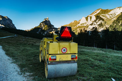 Yellow truck on mountain against clear blue sky