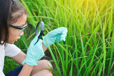 Girl examining plants through magnifying glass