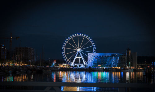 Illuminated bridge over river against sky at night