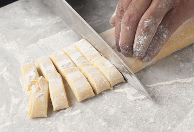 Cropped hands of chef cutting dough on table in commercial kitchen