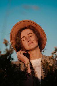 Portrait of smiling young woman against sky