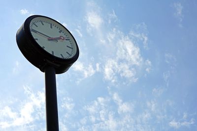 Low angle view of clock on pole against sky