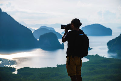 Man photographing on mountain against sky