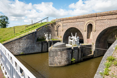 Arch bridge over river against sky