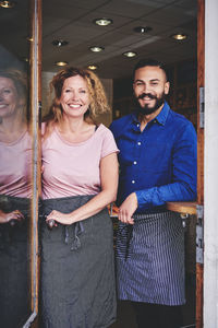 Portrait of smiling colleagues standing at store entrance