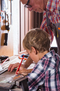 Grandfather teaching carpentry to grandson