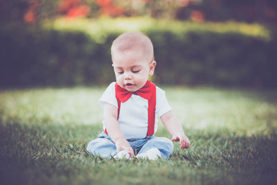 Cute boy sitting on grassy field