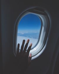 Close-up of hand against airplane window