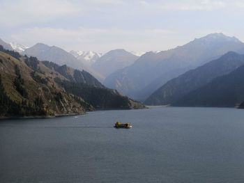 Boat sailing on sea by mountains against sky