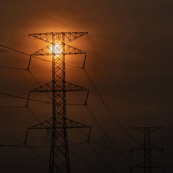 Low angle view of silhouette electricity pylon against sky during sunset