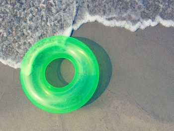 High angle view of green lifeguard ring on sand at beach