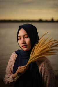 Portrait of a beautiful young woman against lake