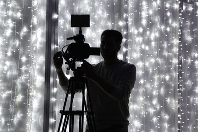 Man photographing against illuminated lights